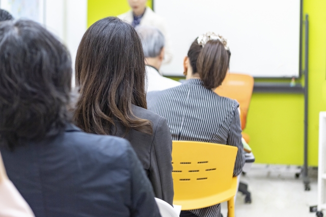 セミナー会場でスーツを着た女性が講演会に参加している写真